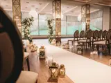 Wedding ceremony aisle in the Grand Ballroom at Boclair House, Glasgow, featuring mirrored floral pillars, white rose arrangements, and a grand crystal chandelier