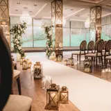 Wedding ceremony aisle in the Grand Ballroom at Boclair House, Glasgow, featuring mirrored floral pillars, white rose arrangements, and a grand crystal chandelier