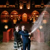 Same sex couple popping a bottle of champagne 