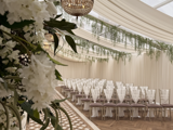 A beautifully arranged wedding ceremony set up the Pavilion at Cornhill Castle in Biggar, Scotland,  featuring floral decorations and elegant seating for guests.