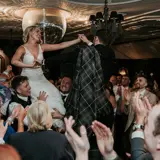 Couple being held up on chairs after ceremony