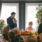 Groom giving a speech and looking at his bride
