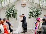 A wedding ceremony taking place at the Pavilion at Cornhill Castle in Biggar, Scotland, featuring an elegant setup with floral decorations and guests in attendance.
