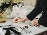 Person setting up elegant glassware on a white table set up at Grand Ballroom at Boclair House, Glasgow