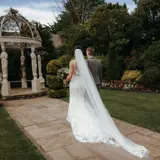 o	Bride and groom walking towards ornate gazebo in beautiful gardens of Scottish venue with late availability wedding packages.
