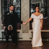 Couple holding hands in front of ornate windows in the hallway of Cornhill Castle