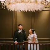 married couple standing under chandelier inside boclair house