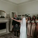 Father getting first look at bride with all bridesmaids