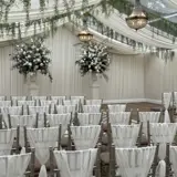 A beautifully arranged wedding ceremony set up inside the Pavilion at Cornhill Castle in Biggar, Scotland,  featuring rows of elegant seating and  floral decorations.