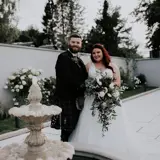 Couple standing smiling behind fountain at The Garden House