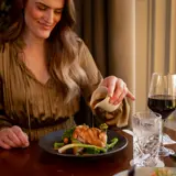 Woman pouring gravy on dinner at Cornhill Castle