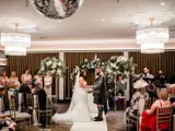 Wedding couples saying their vows at the top of the aisle in The Grand Ballroom at The Redhurst, Giffnock