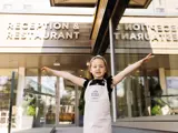 Child with Bird and Bell apron outside restaurant