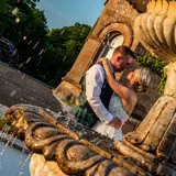 Couple cuddling behind fountain