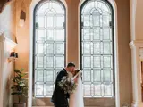 Couple kissing in front of arch windows at the front of the castle
