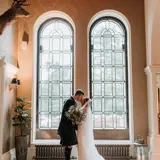 Couple kissing in front of arch windows at the front of the castle