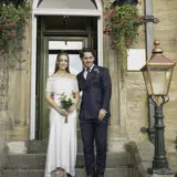 A bride and groom pose together in front of the Lynnhurst Hotel, celebrating their wedding day with smiles and elegant attire.