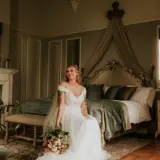 Bride in her dress sitting on bed in Honeymoon Suite